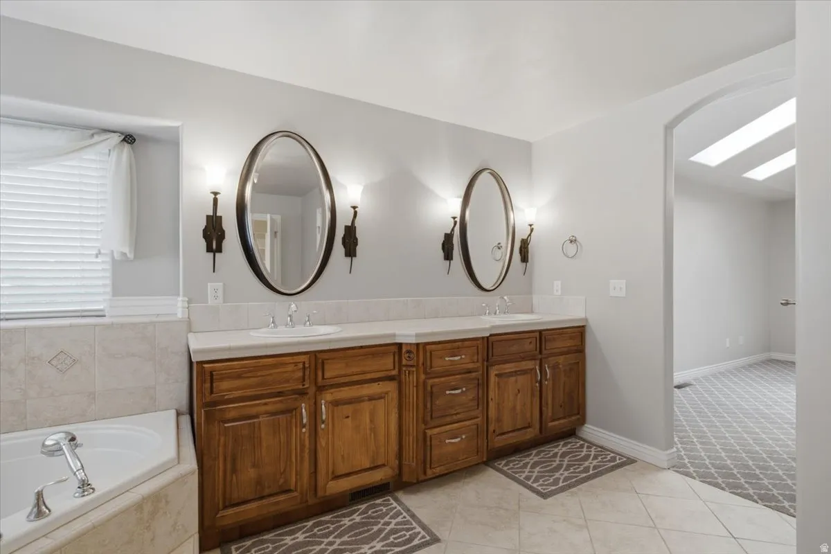 Dual vanities with integrated sinks, rich wood cabinetry, and wall-mounted sconces