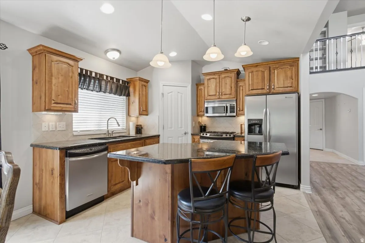 Wood-finish cabinetry with dark countertops, stainless steel appliances, and a built-in kitchen island