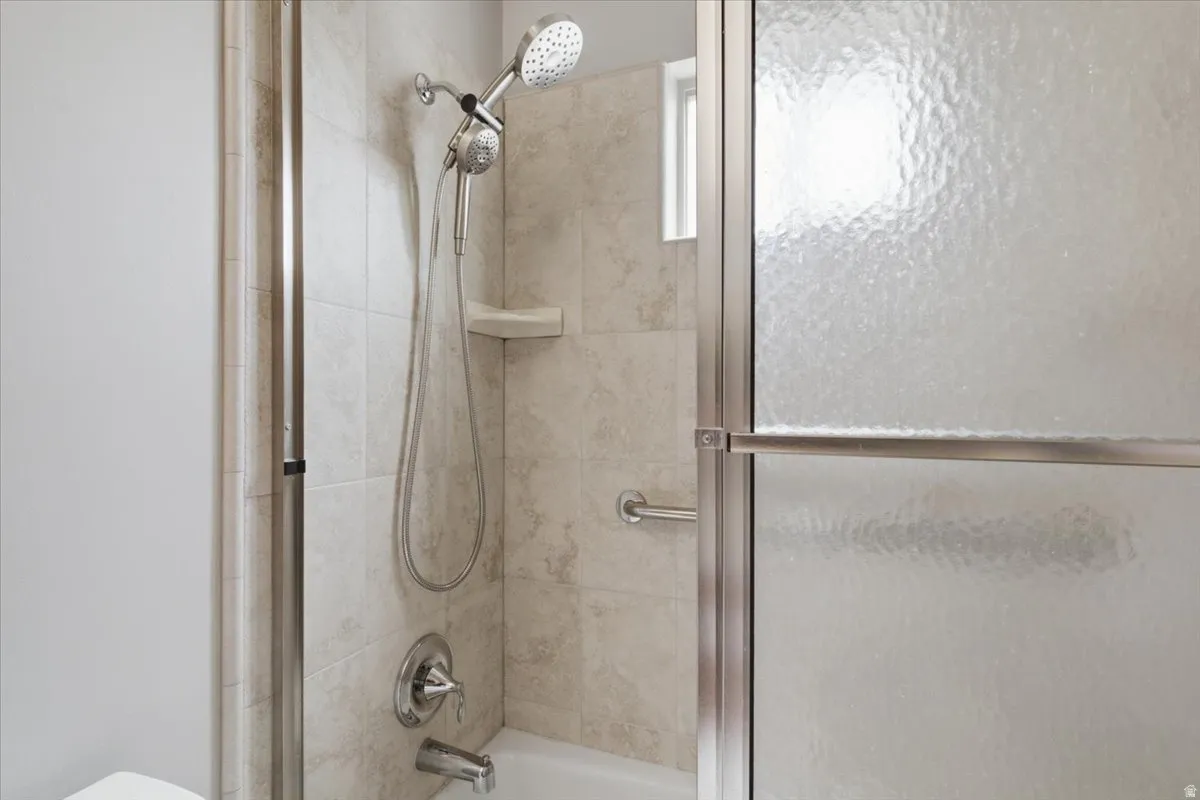 Bathtub shower combination with a handheld shower head, tiled surround, and integrated soap dish