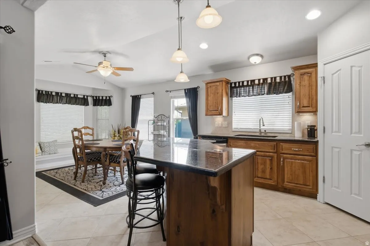Kitchen featuring wood cabinetry, a center island with a dark countertop, and tile flooring