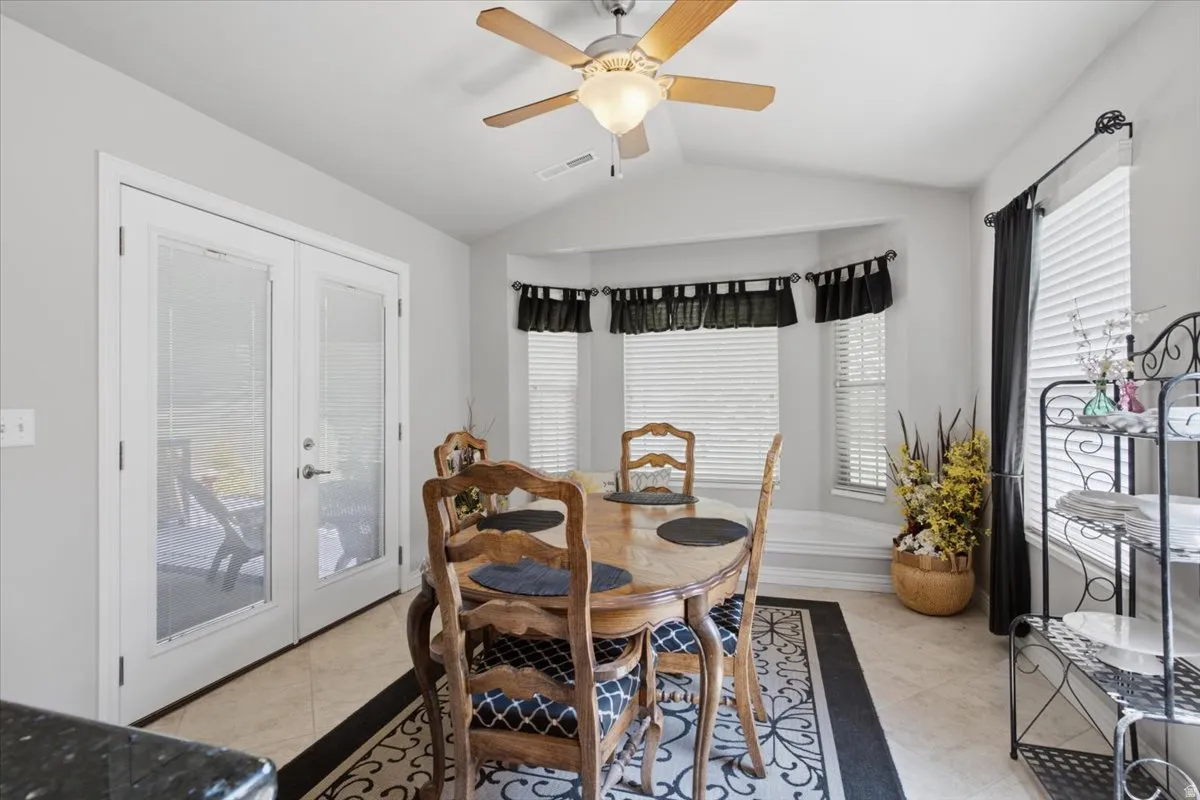 Neutral wall paint, tiled flooring, ceiling fan with integrated lighting, bay window, and glass-paneled double doors