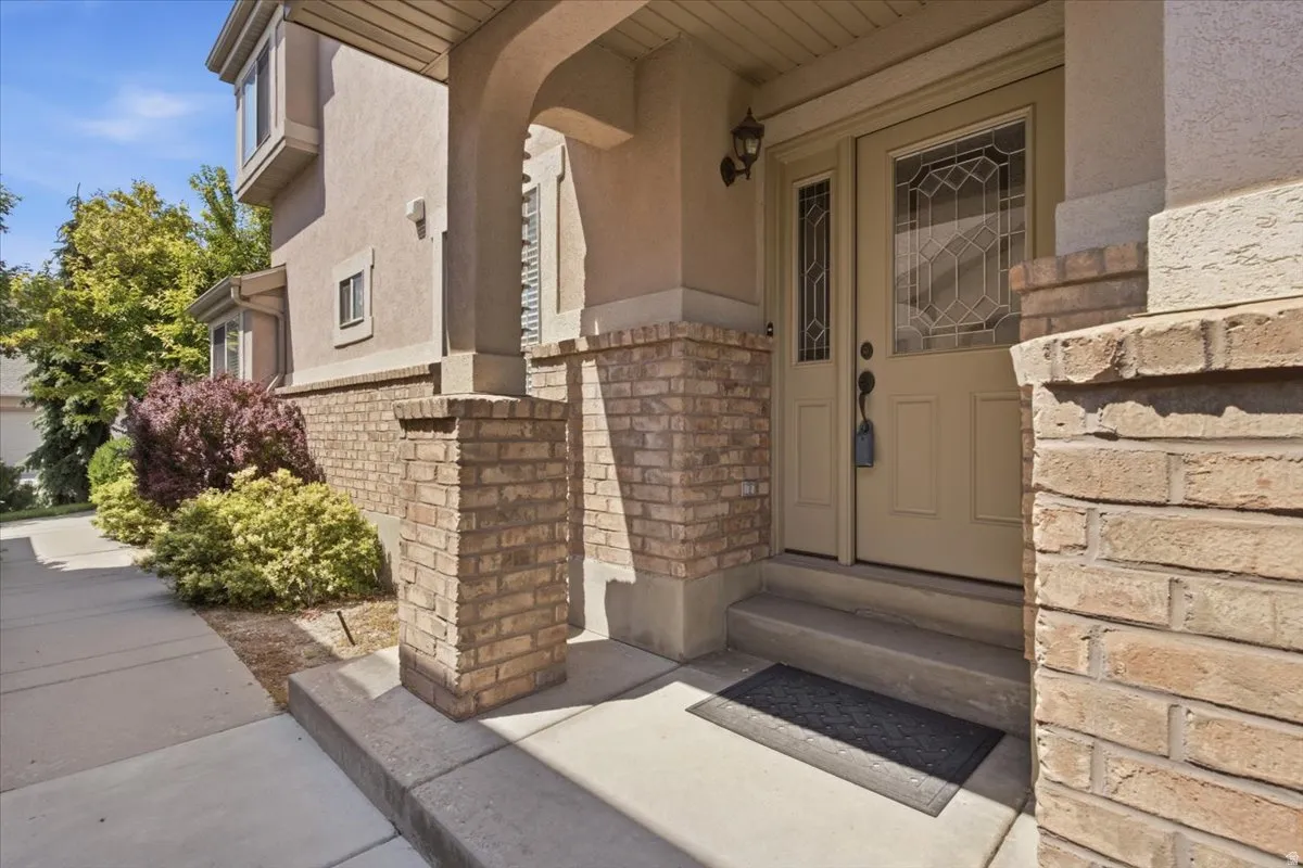 Stucco exterior with brick accents, concrete walkway, and established landscaping