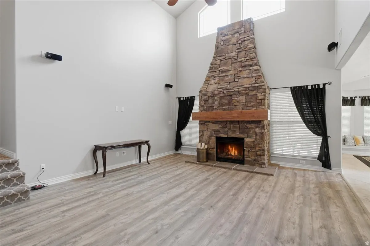 Vaulted ceiling, stone-clad fireplace with wood mantel, built-in fireplace, wood-finish flooring, and upper transom windows
