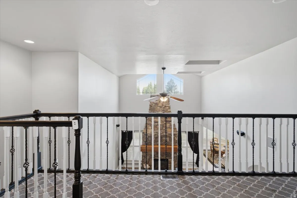 Open-concept loft area featuring a decorative wrought iron railing, recessed lighting, and an arched window