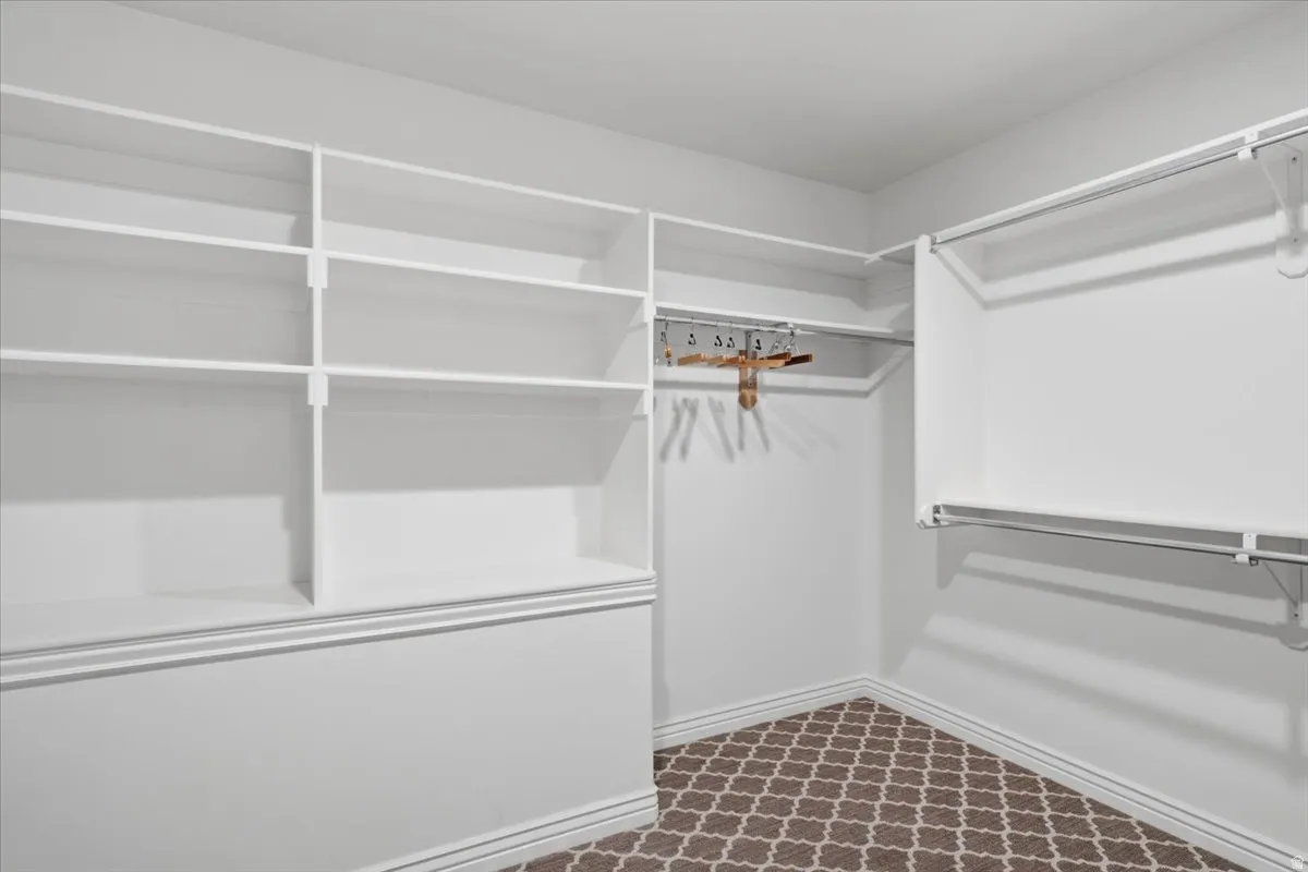 Built-in shelving, multiple hanging rods, corner configuration, white finishes, and patterned carpeting
