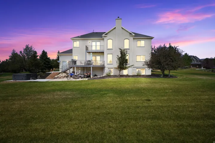 Expansive rear elevation featuring a multi-level deck, a lower patio, and a grass lawn