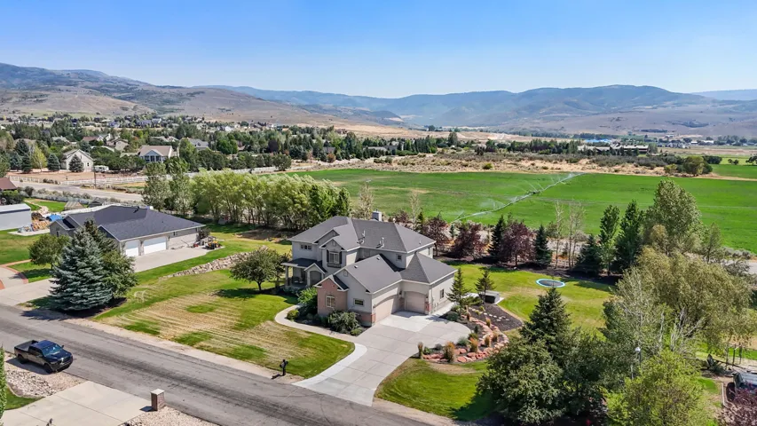 Multi-level residence with an attached three-car garage, mature landscaping, and a paved driveway