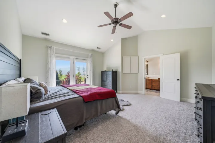 Vaulted ceiling, recessed lighting, ceiling fan, carpeted flooring, and balcony access