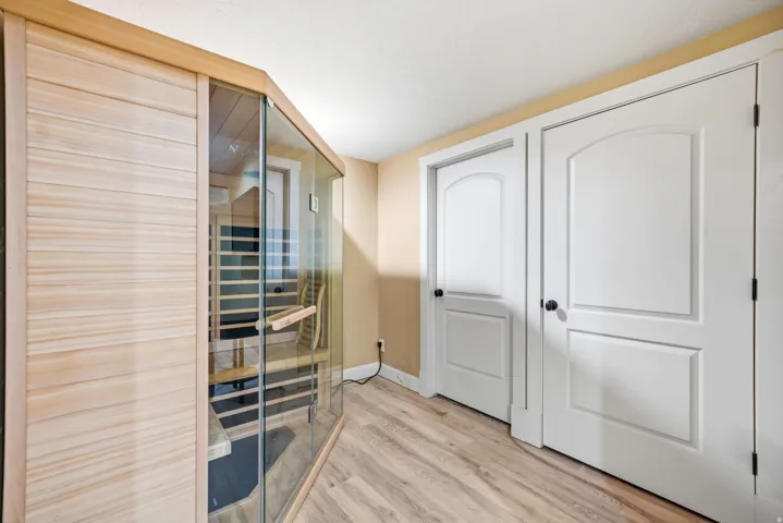 Wood-finish flooring with a built-in sauna featuring clear glass panels and wood slat walls