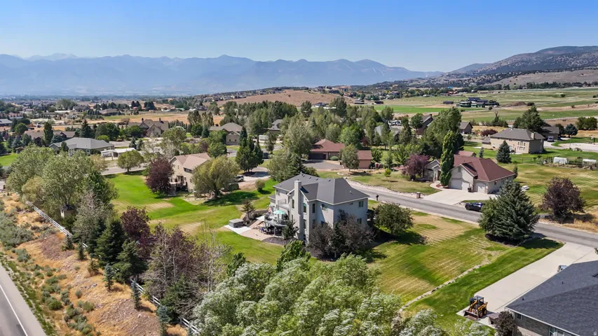 Expansive property with mature trees, green lawns, and distant mountain backdrops