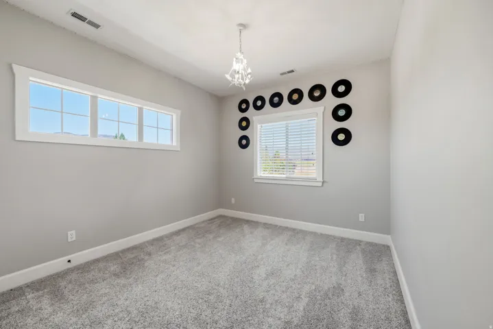Soft gray wall paint, plush carpeting, two windows, and a decorative ceiling light fixture