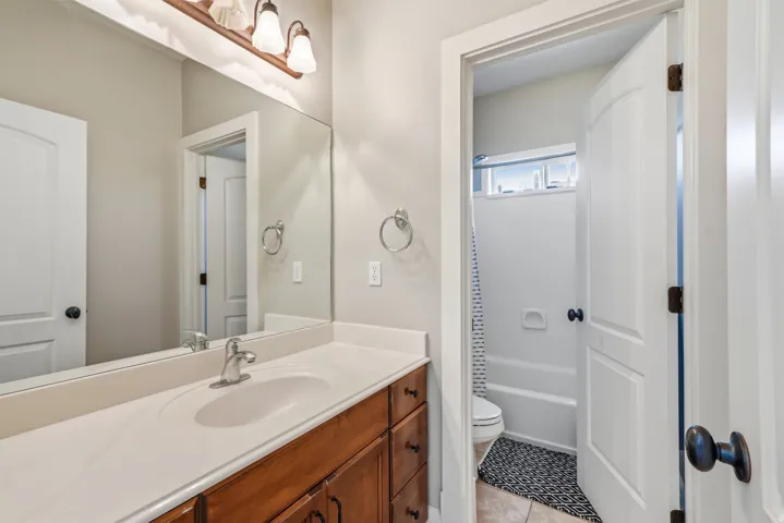 Wood-finish vanity with a white countertop and integrated sink basin, brushed nickel faucet, and overhead lighting fixture