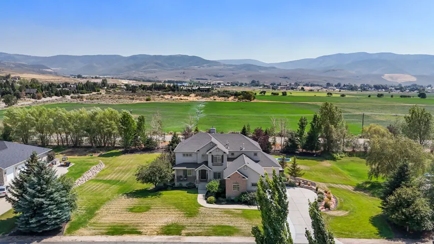 Expansive property with a multi-level residence, mature landscaping, and a mountain backdrop