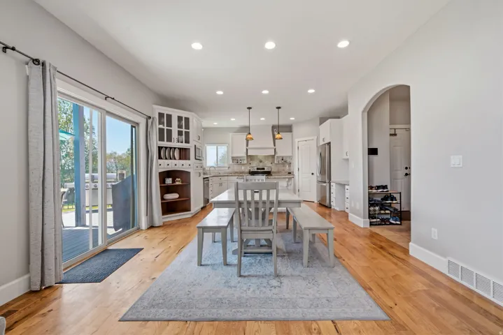Wood-finish flooring, recessed lighting, and a white kitchen with shaker cabinets and stainless steel appliances