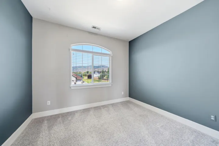 Arched window with blinds, carpeted flooring, and painted walls