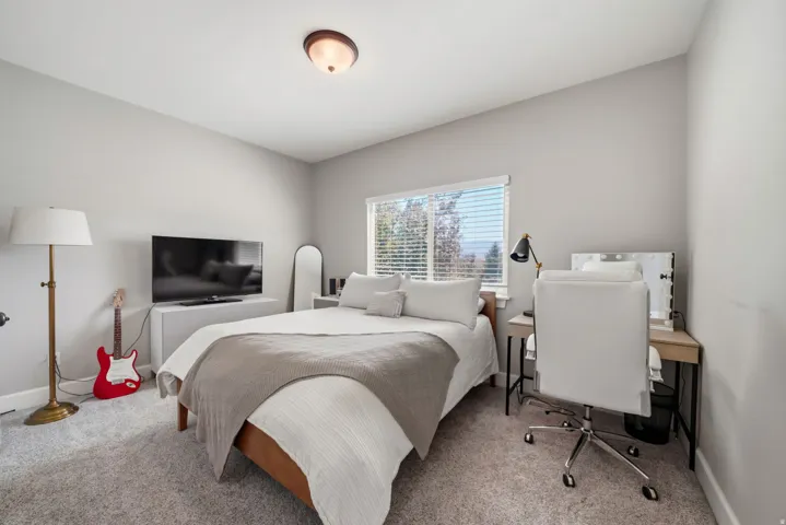 Carpeted bedroom featuring a large window with blinds, light gray wall paint, and a semi-flush mount ceiling light