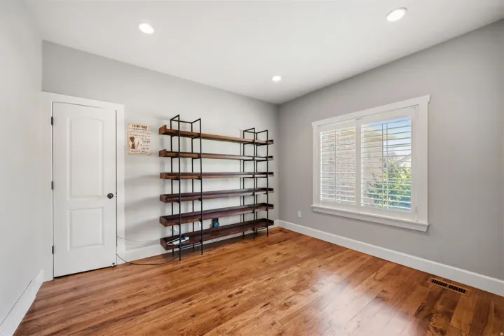 Hardwood flooring, recessed ceiling lighting, window with plantation shutters, white interior door, and trim detailing