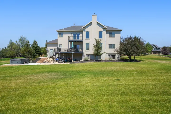 Stucco exterior with a multi-level deck, ground-level patio, and a standalone spa