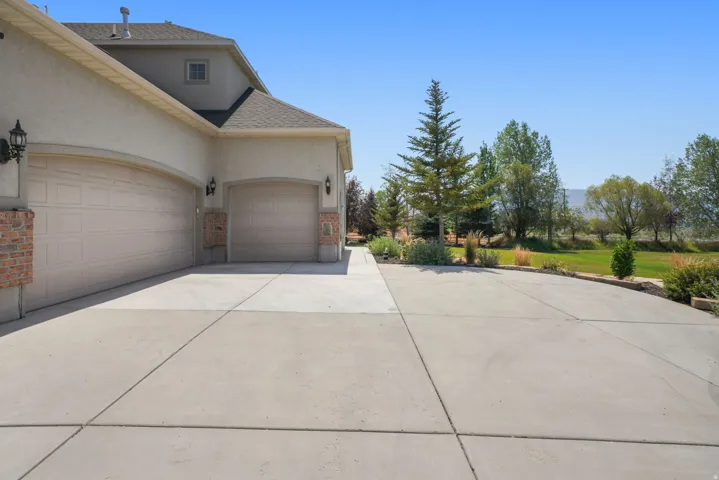 Exterior featuring a two-car garage, an additional single-car garage, brick accents, stucco siding, and a concrete driveway
