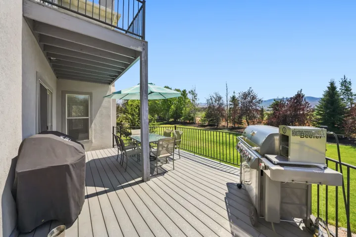 Ground-level deck with composite wood-finish flooring, black metal railings, and a stucco exterior
