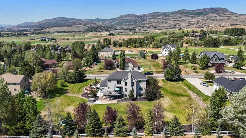 Expansive property with a multi-level deck, mature landscaping, and an integrated hardscape patio