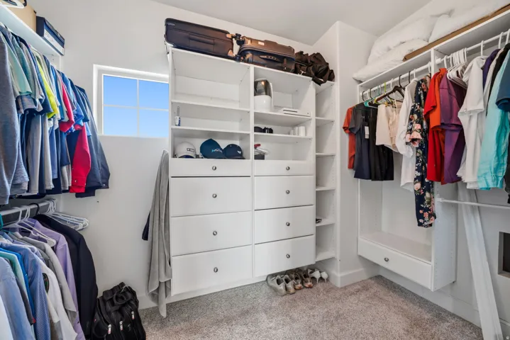 Custom closet system featuring built-in drawers, open shelving, and extensive hanging rods
