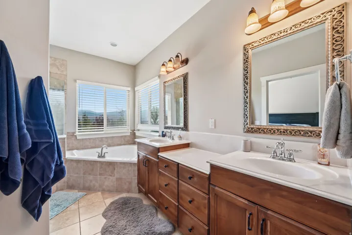 Dual vanity with white countertops, wood-finish cabinetry, and decorative framed mirrors