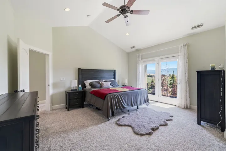 Vaulted ceilings, recessed lighting, ceiling fan, carpet flooring, and double French doors to an exterior balcony