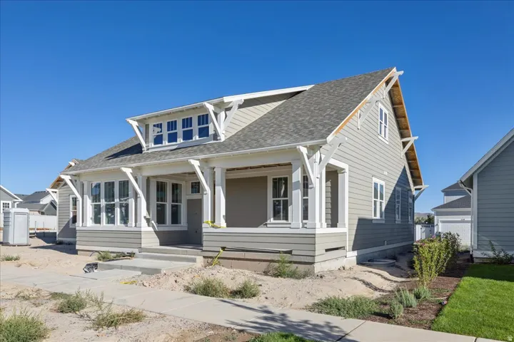 Craftsman-style home featuring a covered front porch, light gray siding, white trim, and a gray shingle roof
