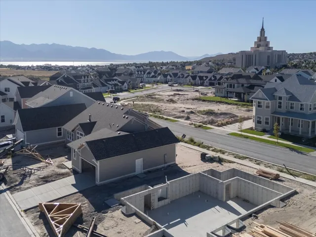 Aerial perspective of a developing residential area with existing homes, a large building with a spire, and mountains in the distance
