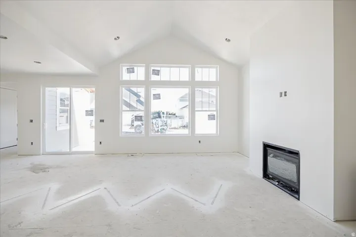 Vaulted ceiling with recessed lighting, large multi-pane windows, built-in fireplace, and sliding glass door
