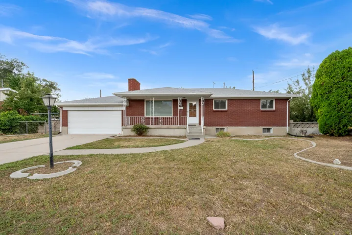 Red brick exterior with a front porch, white railing, and a two-car garage
