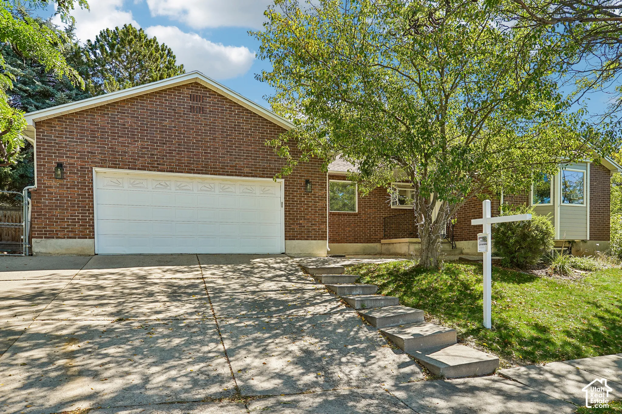 Brick exterior with an attached garage, featuring a concrete driveway and walkway