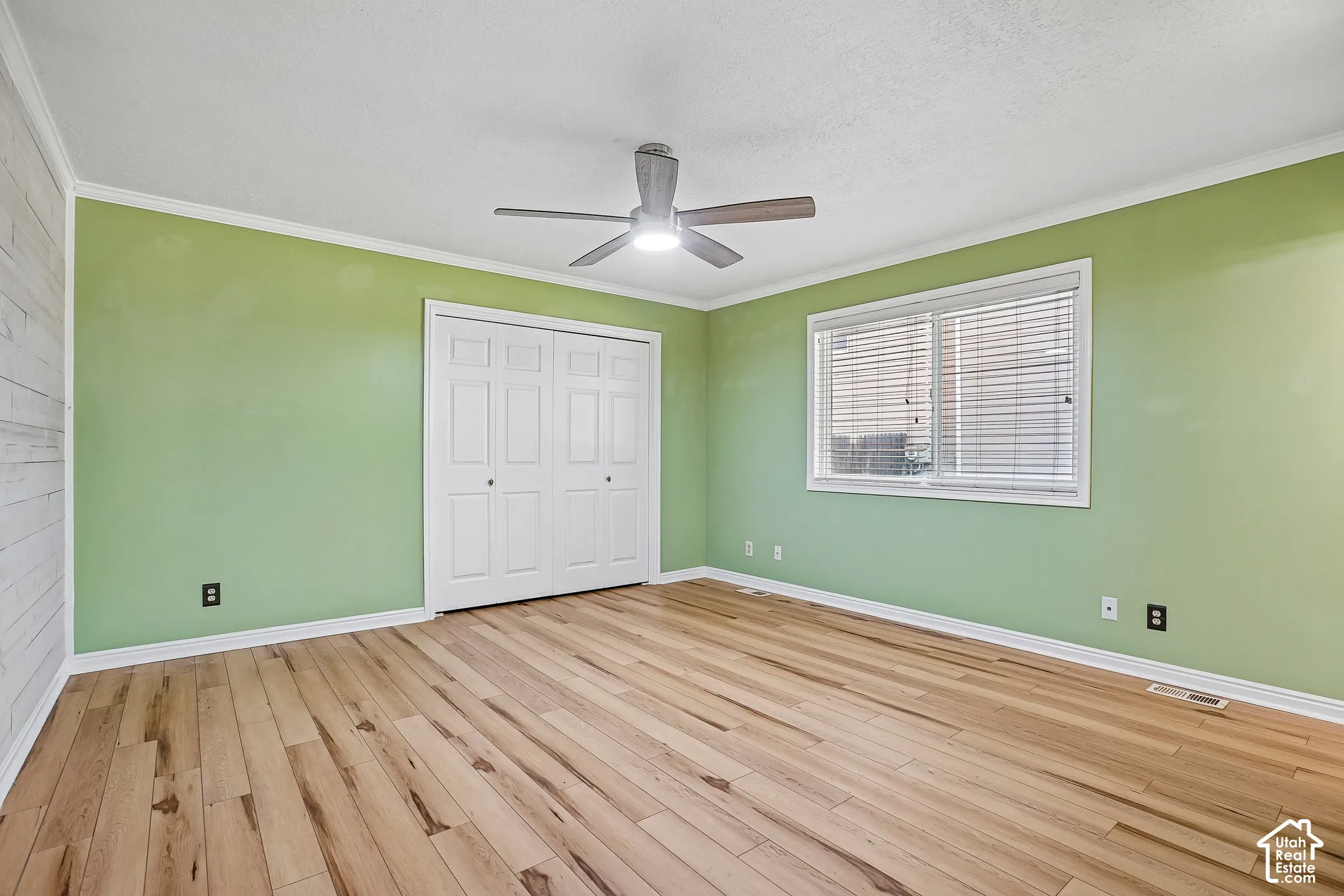 Wood-finish flooring, ceiling fan, white trim, sliding closet doors, and a window with blinds
