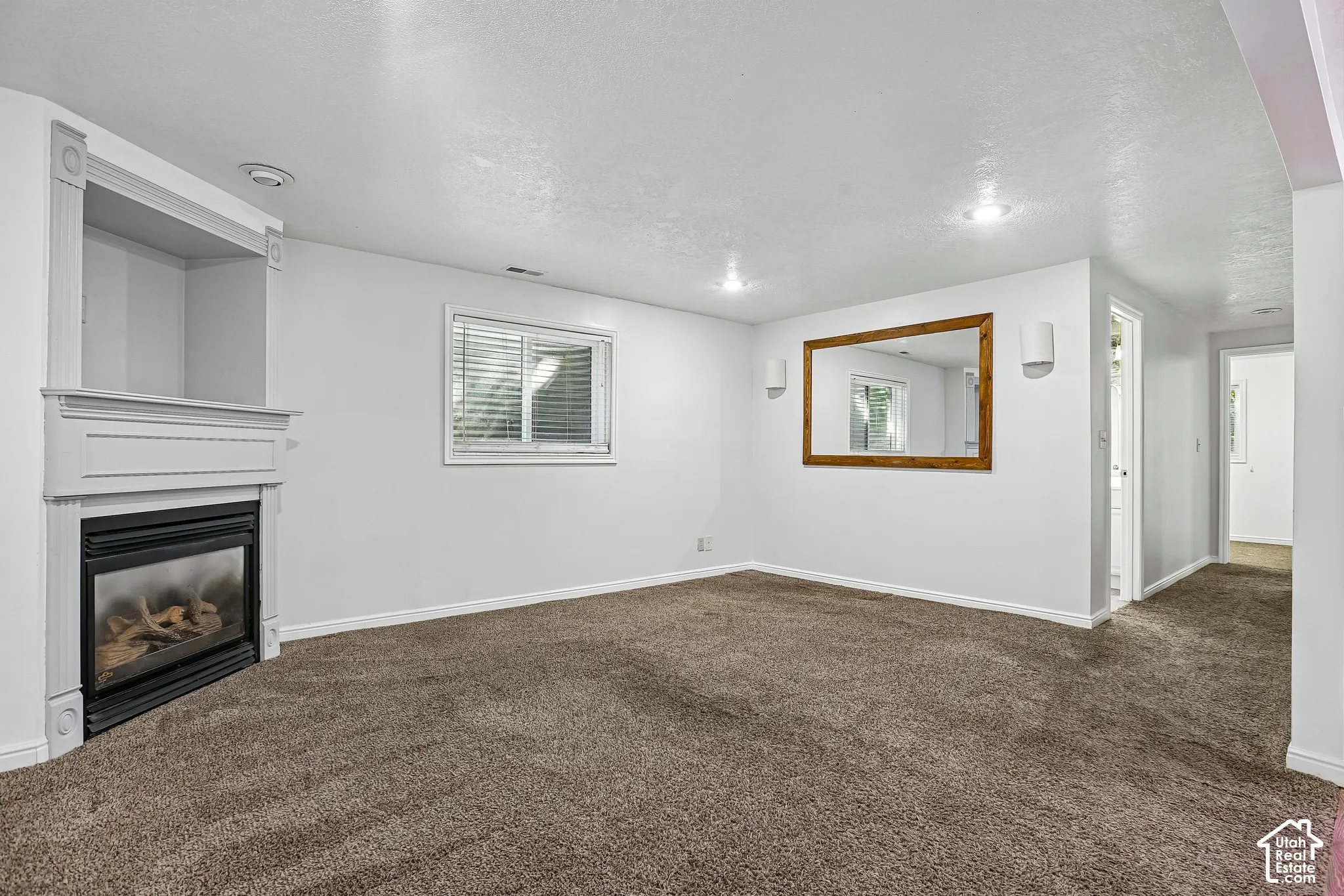 Built-in fireplace with a white mantel, inset display niche, recessed lighting, and soft carpet flooring