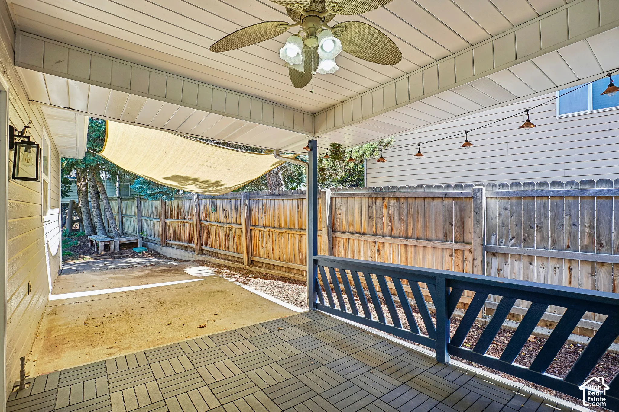 Covered patio with a ceiling fan, outdoor wall lantern, and string lighting