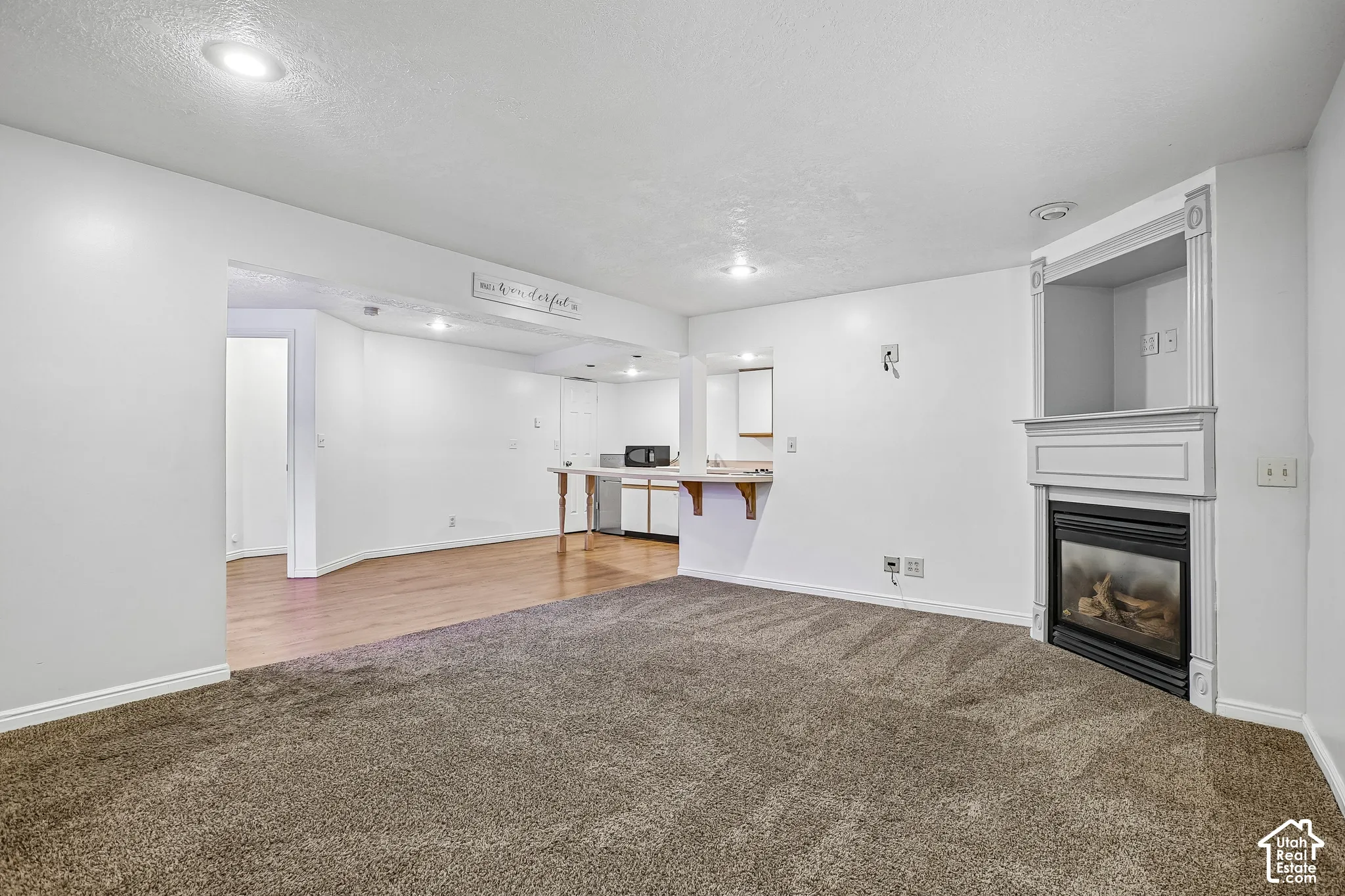 Recessed lighting, wood-finish flooring, and a built-in fireplace with a decorative mantel and hearth