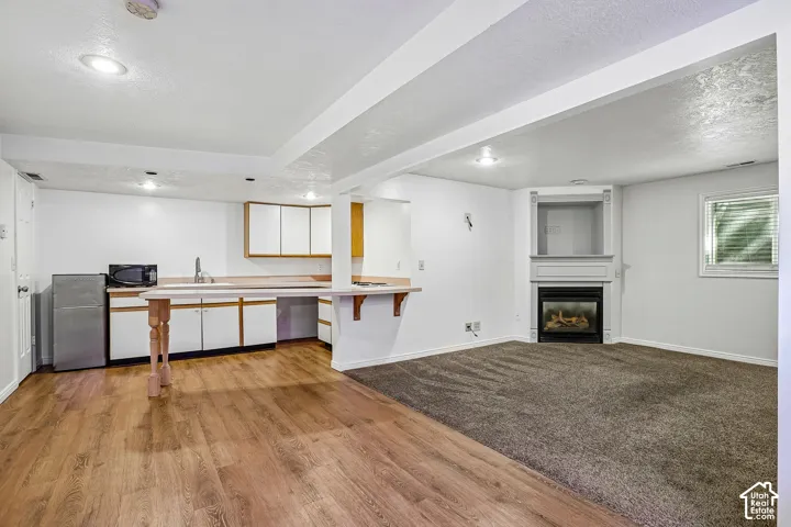 Built-in fireplace with a mantel, wood-finish flooring, white cabinetry, and recessed lighting