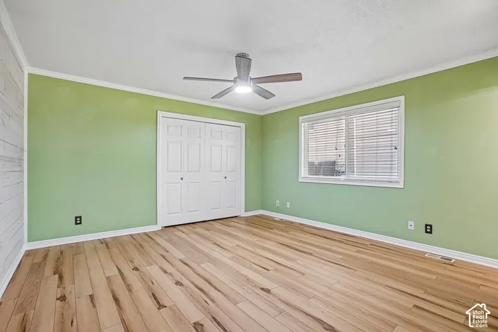 Wood-finish flooring, ceiling fan, white trim, sliding closet doors, and a window with blinds