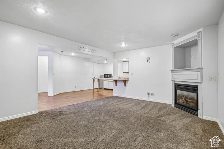 Recessed lighting, wood-finish flooring, and a built-in fireplace with a decorative mantel and hearth