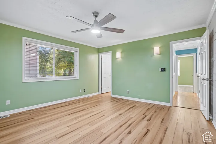 Wood-finish flooring, a window with blinds, a ceiling fan with integrated lighting, and two wall-mounted sconces