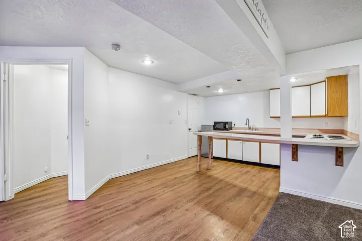 Kitchenette with white cabinetry, a single basin sink, and an integrated cooktop