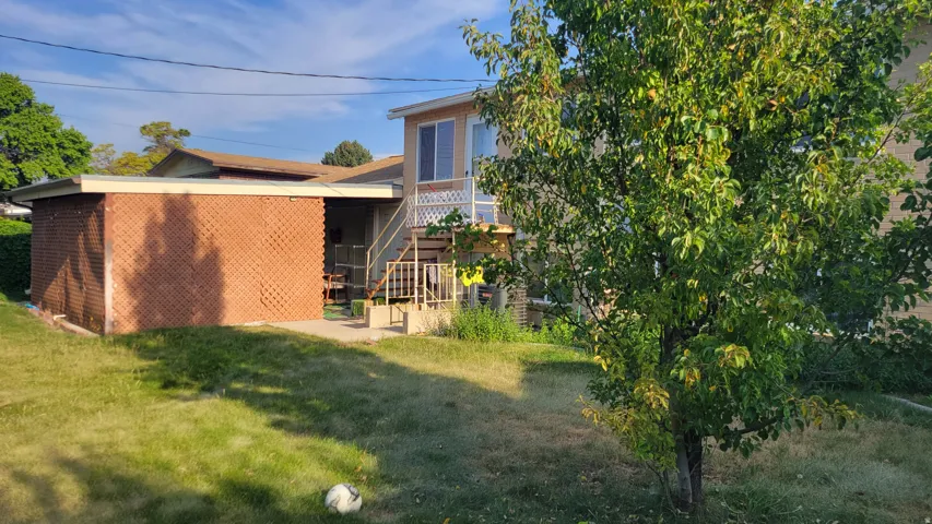 Rear exterior with brick-patterned siding, upper-level balcony, and exterior stairs