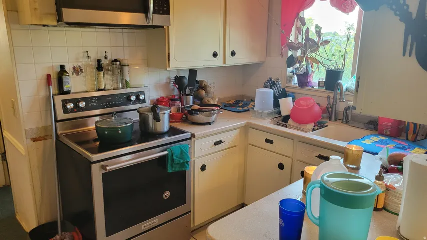 Kitchen featuring a white tile backsplash, a stainless steel range, and cream-colored cabinetry