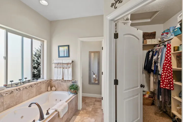 Soaking tub with bronze-finish fixtures, tile surround, and frosted window