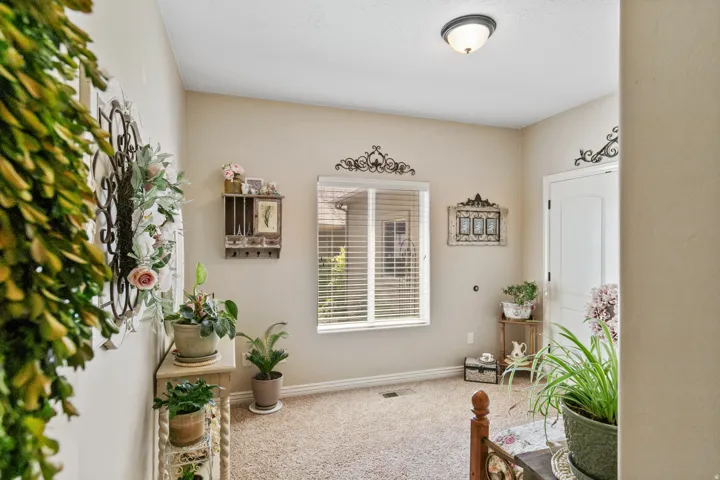 Carpeted room with a double-pane window featuring horizontal blinds, neutral wall paint, and a white interior door