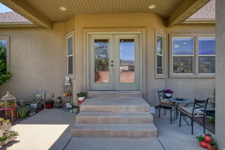 Entryway featuring double glass-panel doors, multiple windows with blinds, and a covered concrete patio