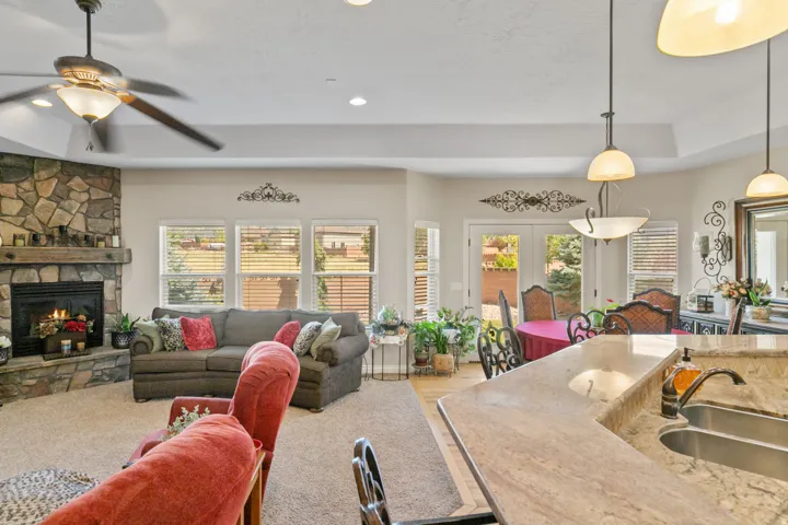 Open-concept living area with a stone-clad fireplace and wood mantel