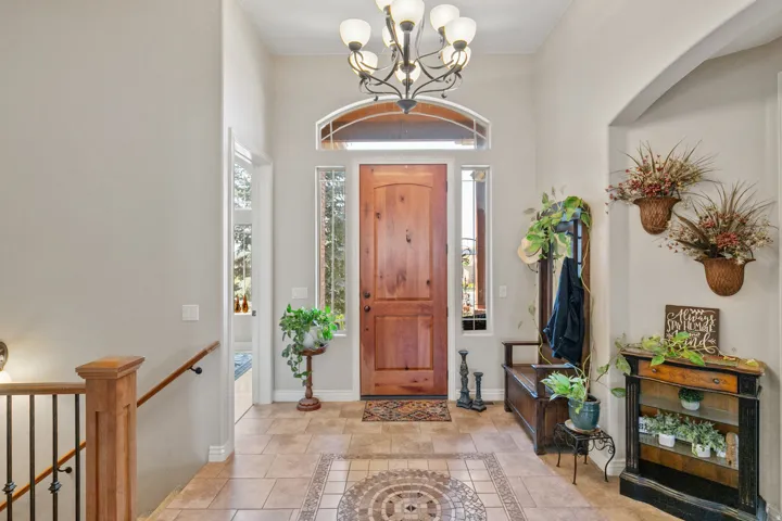 Foyer featuring a wood entry door, arched transom window, and tile flooring with an inset mosaic
