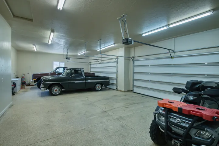 Expansive garage featuring multiple automatic overhead doors, concrete flooring, and ample overhead lighting